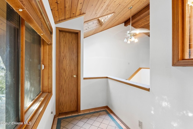 interior space featuring lofted ceiling with skylight, wood ceiling, baseboards, and light tile patterned floors