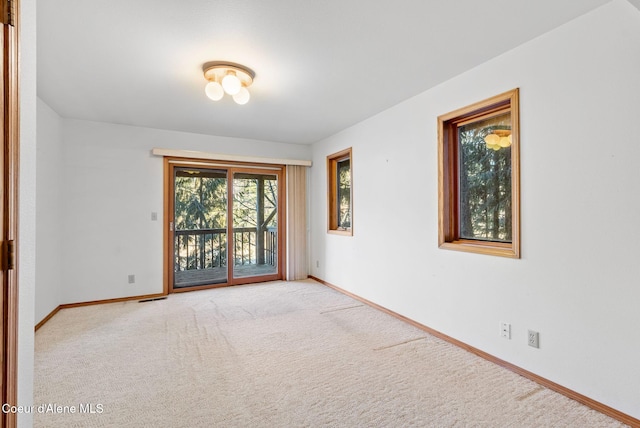 empty room featuring light carpet and baseboards