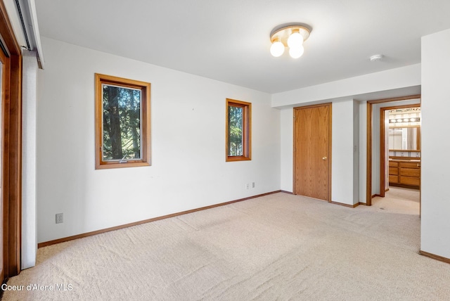 unfurnished bedroom with light carpet, multiple windows, baseboards, and a closet