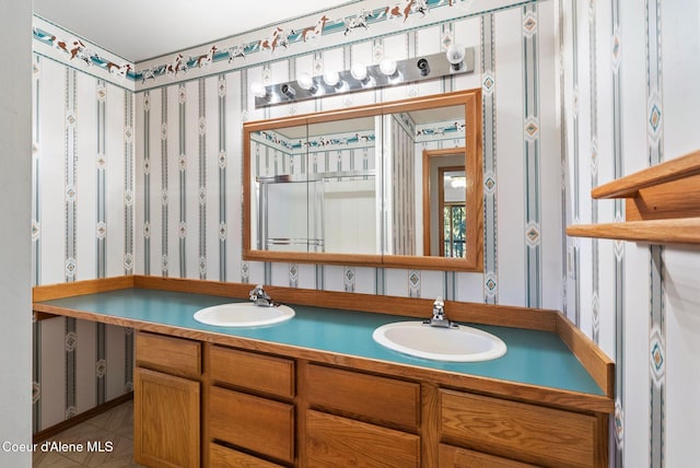 bathroom featuring tile patterned flooring, double vanity, a sink, and wallpapered walls