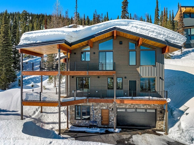 exterior space with stone siding, an attached garage, and a balcony