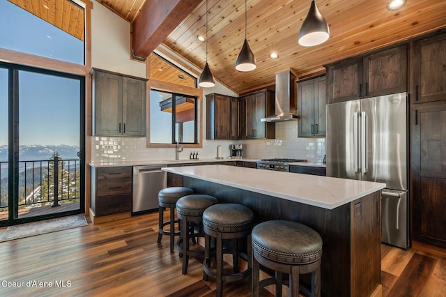 kitchen featuring stainless steel appliances, dark brown cabinetry, wall chimney range hood, and tasteful backsplash