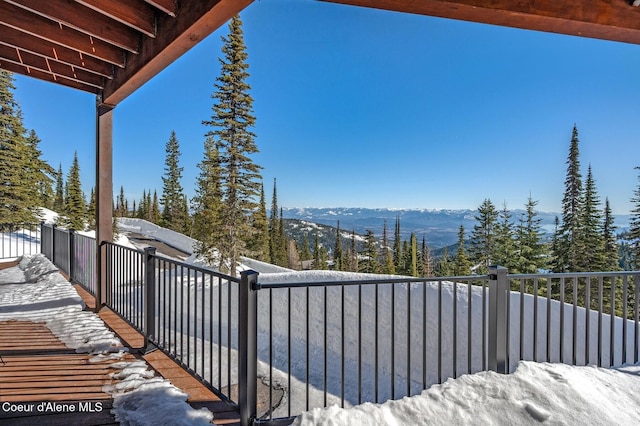 yard layered in snow with a mountain view and a balcony