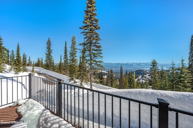 snow covered back of property featuring a mountain view and a wooded view