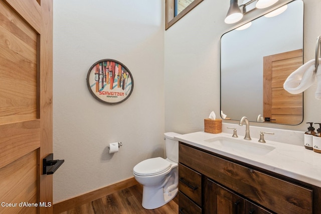 bathroom with toilet, baseboards, wood finished floors, and vanity