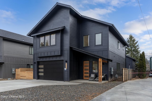 contemporary home featuring an attached garage, driveway, and fence