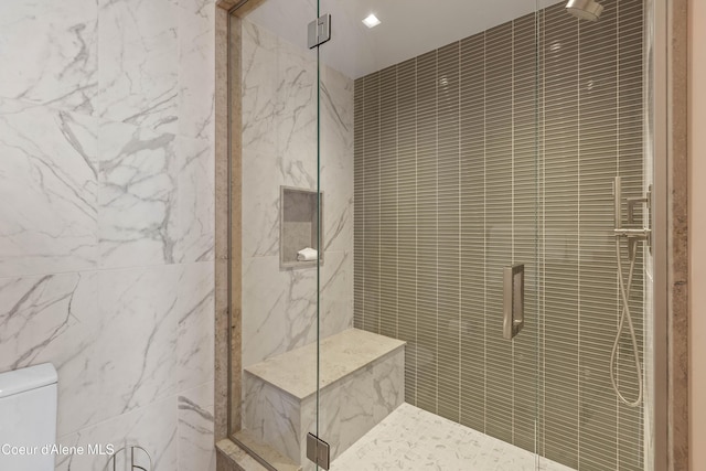 bathroom featuring a marble finish shower, toilet, and tile walls