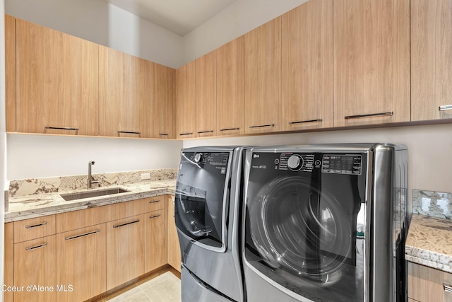 washroom with light tile patterned flooring, independent washer and dryer, a sink, and cabinet space