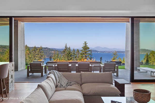 living room with floor to ceiling windows, a water and mountain view, and wood finished floors