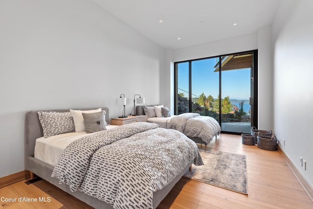 bedroom with access to exterior, recessed lighting, wood finished floors, high vaulted ceiling, and baseboards