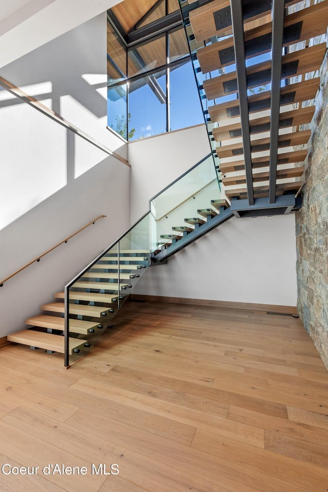 stairway with a towering ceiling and wood finished floors