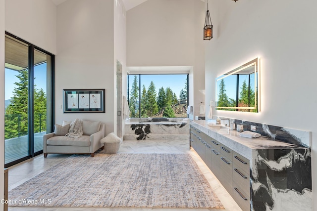 bathroom with marble finish floor, a healthy amount of sunlight, a towering ceiling, and vanity