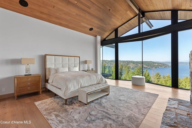 bedroom with vaulted ceiling with beams, a water view, light wood-style floors, a wall of windows, and wooden ceiling