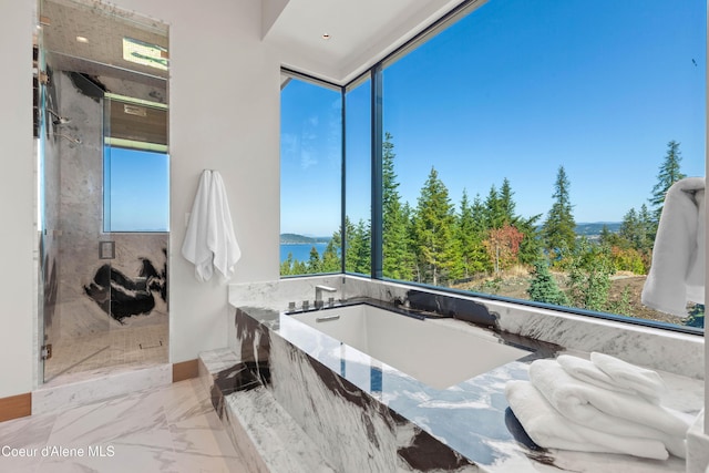 bathroom with marble finish floor, a shower, a tub with marble appearance, and a wealth of natural light