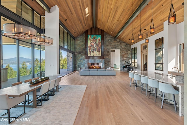 dining space featuring a large fireplace, light wood finished floors, wooden ceiling, high vaulted ceiling, and a mountain view