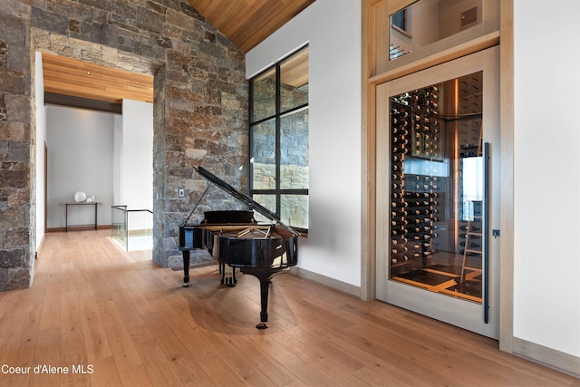 wine cellar with high vaulted ceiling, wooden ceiling, wood finished floors, and baseboards