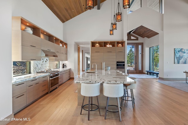 kitchen with light stone counters, stainless steel appliances, a sink, modern cabinets, and a kitchen breakfast bar