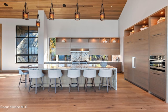 kitchen featuring high vaulted ceiling, modern cabinets, oven, and decorative light fixtures