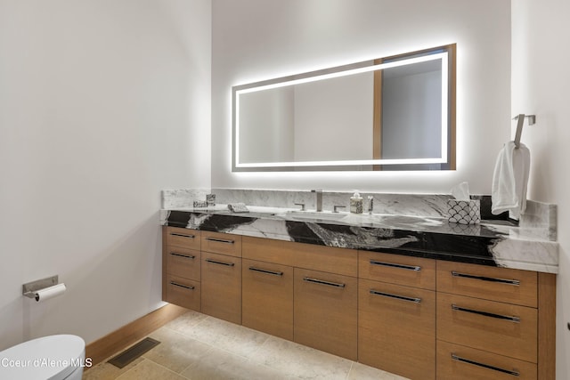 half bath featuring toilet, vanity, visible vents, baseboards, and tile patterned floors