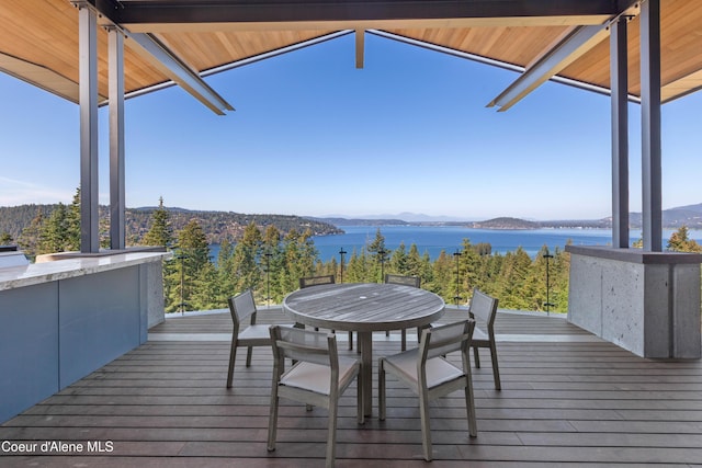 wooden terrace featuring a water and mountain view and outdoor dining space