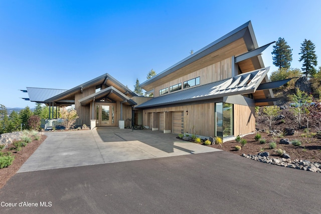 view of front facade featuring a garage, driveway, and metal roof