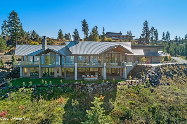 rear view of house featuring metal roof, a standing seam roof, and a chimney