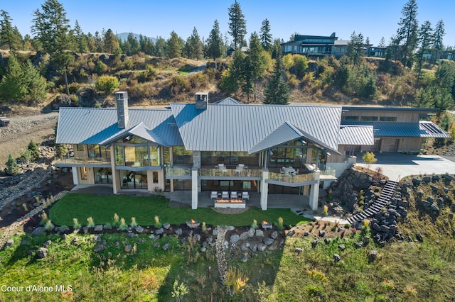 rear view of house featuring a chimney, metal roof, a patio, and a yard