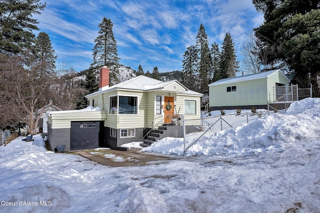 315 Montana St, Mullan, ID 83846 - view of front of property featuring a garage, a chimney, metal roof, an outbuilding, and fence