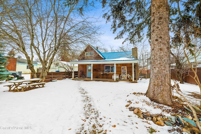 view of front of house featuring covered porch, metal roof, and fence