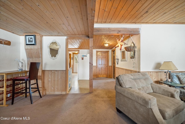 living area with beam ceiling, a wainscoted wall, light carpet, wooden walls, and wooden ceiling