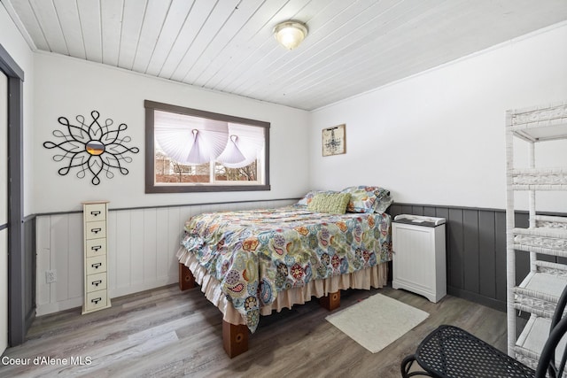 bedroom featuring wooden ceiling, a wainscoted wall, and light wood finished floors