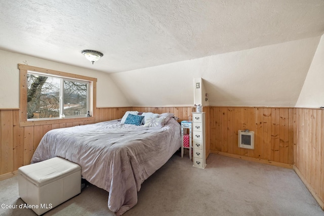 bedroom with lofted ceiling, wooden walls, a textured ceiling, and light colored carpet