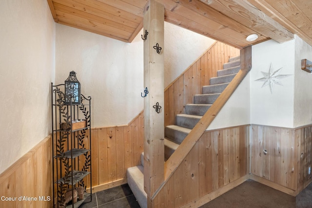 staircase with a wainscoted wall, vaulted ceiling, wood ceiling, and wooden walls