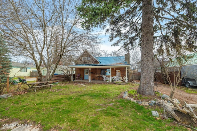 329 S Florence Ave, Sandpoint, ID 83864 - rear view of property featuring a chimney, fence, a porch, a lawn, and metal roof