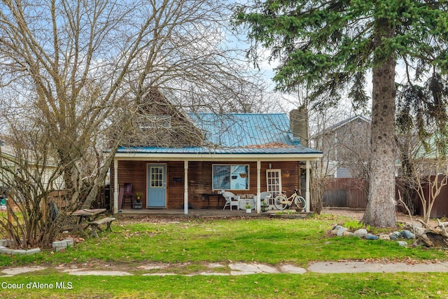 329 S Florence Ave, Sandpoint, ID 83864 - view of front of house with a front lawn, a chimney, metal roof, covered porch, and fence