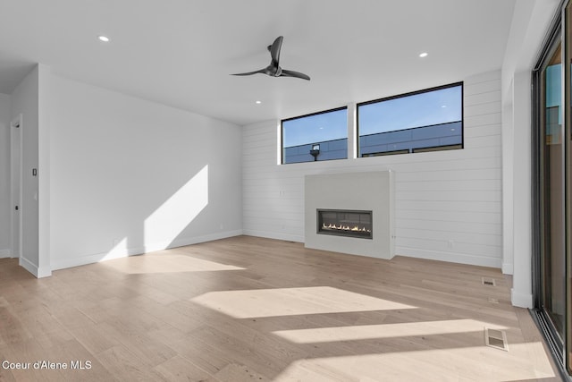 unfurnished living room featuring a glass covered fireplace, ceiling fan, recessed lighting, and wood finished floors