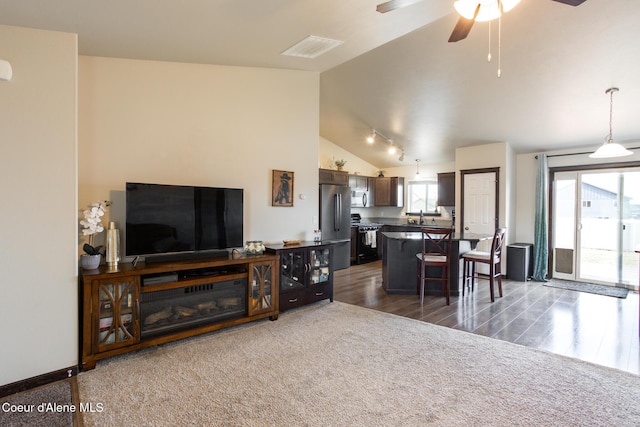 living area with a healthy amount of sunlight, ceiling fan, visible vents, and lofted ceiling