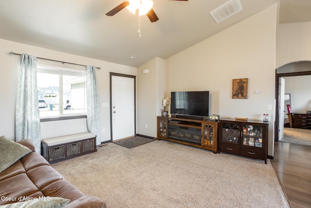 carpeted living room with ceiling fan, visible vents, vaulted ceiling, and baseboards