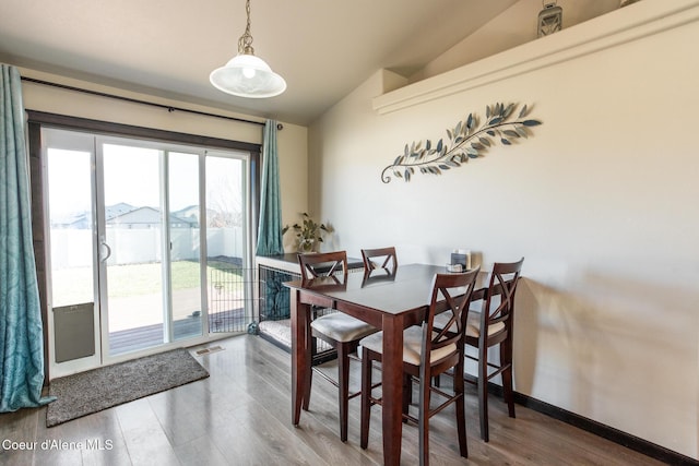 dining room featuring baseboards, visible vents, vaulted ceiling, and wood finished floors