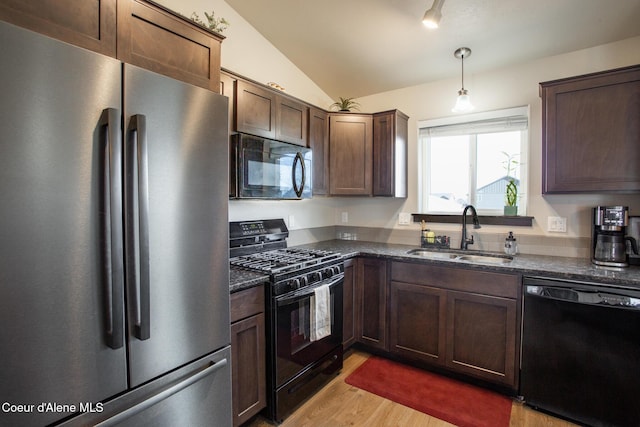 kitchen with lofted ceiling, light wood-style flooring, a sink, dark stone counters, and black appliances