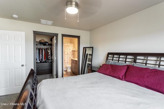 bedroom with ensuite bathroom, visible vents, a ceiling fan, a spacious closet, and a closet