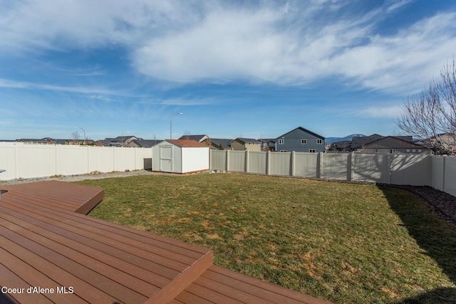 view of yard featuring a storage shed, a deck, an outbuilding, and a fenced backyard