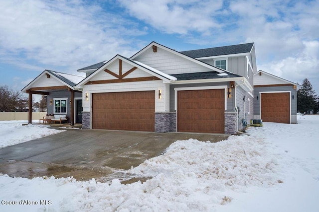 craftsman-style house featuring an attached garage, cooling unit, stone siding, driveway, and board and batten siding