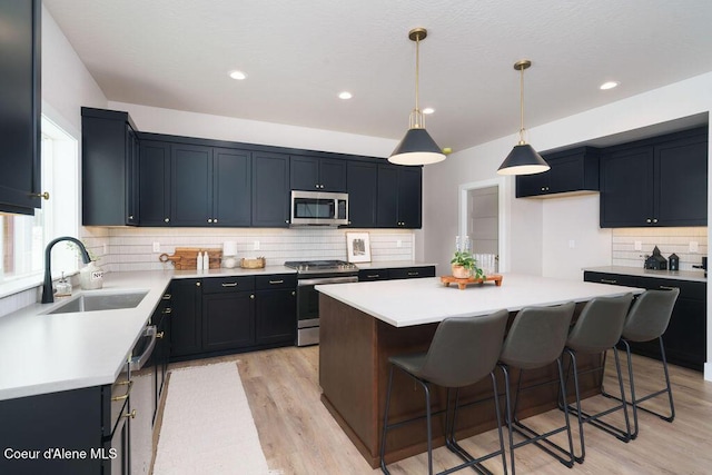 kitchen featuring a sink, a kitchen island, stainless steel appliances, and light countertops