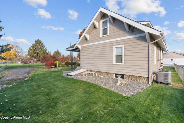 view of side of home with a lawn, cooling unit, and fence