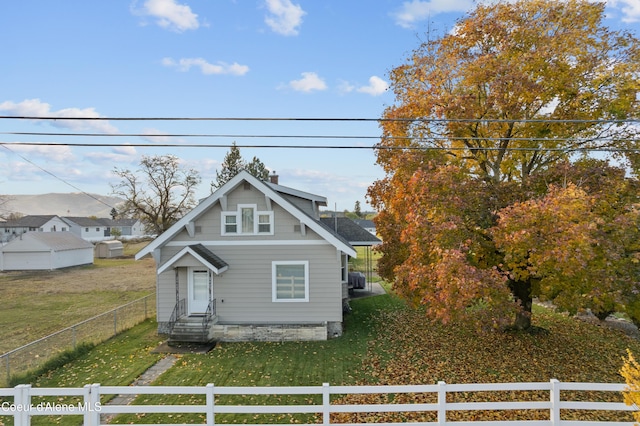 view of front facade featuring a fenced front yard, entry steps, a chimney, and a front lawn