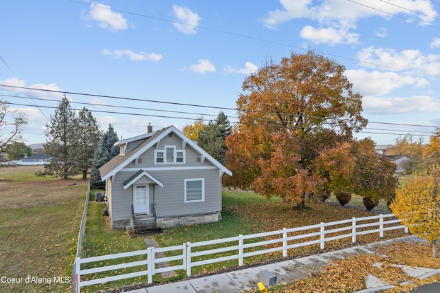 view of front of home with a fenced front yard, a chimney, and a front lawn