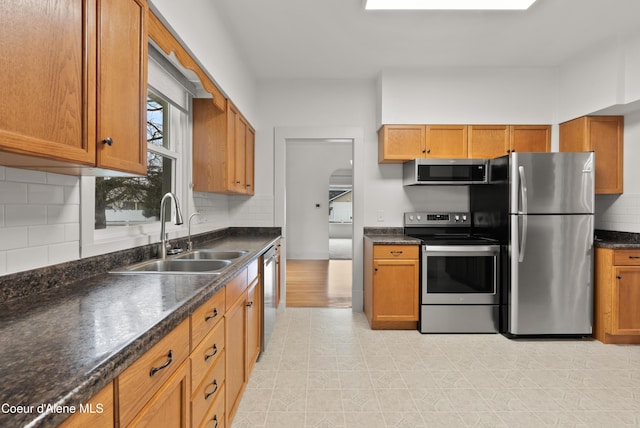 kitchen featuring a sink, appliances with stainless steel finishes, and brown cabinetry