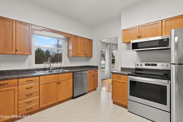 kitchen featuring a wealth of natural light, backsplash, stainless steel appliances, and a sink