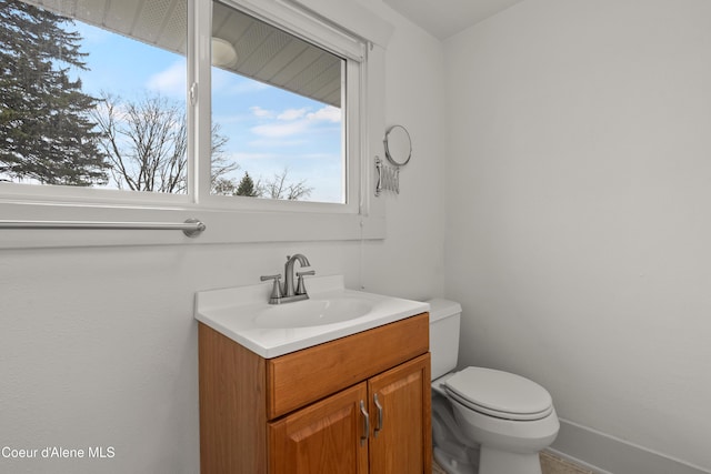 half bath with toilet, vanity, and baseboards